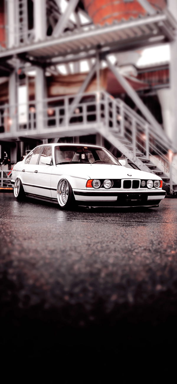 خلفية سيارة BMW كلاسيكية متوقفة في ساحة صناعية للجوال