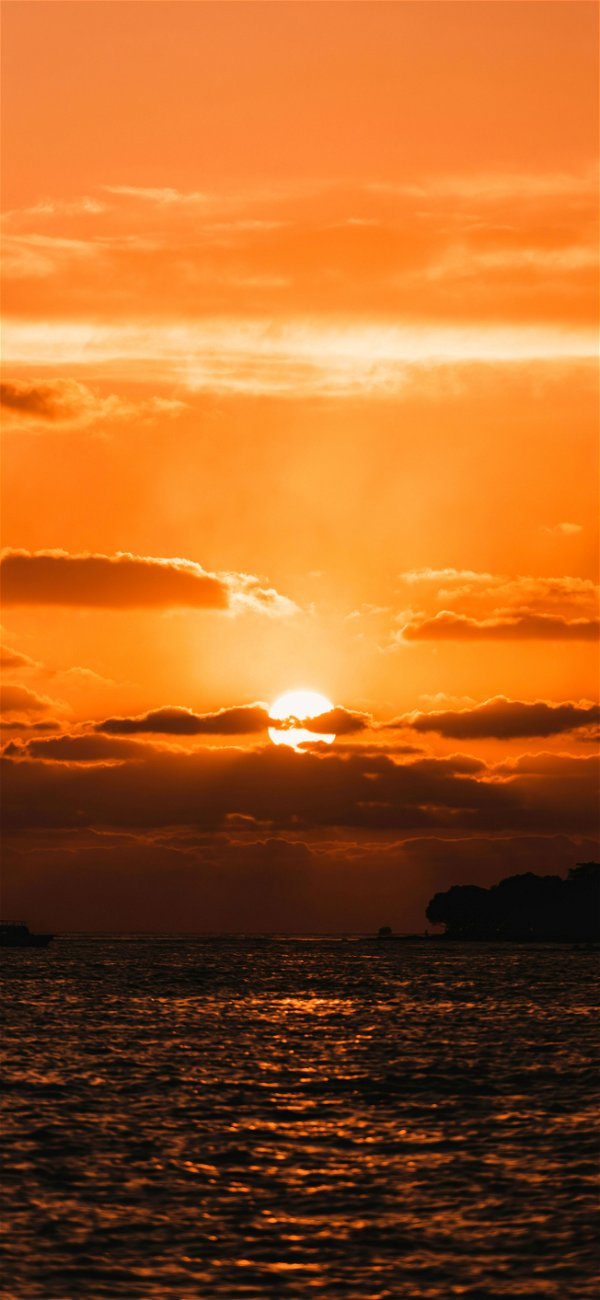 خلفية شمس تغرب وراء الغيوم فوق البحر القاتم للجوال