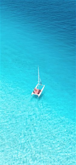 خلفية  قارب صغير في مياه البحر الفيروزية الصافية  للجوال