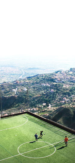 خلفية  لاعبي كرة قدم يتمرنون على الملعب الاخضر فوق قمة الجبل  لهواتف سامسونج
