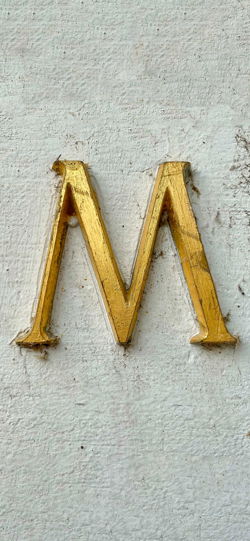 خلفية  حرف M ذهبي على جدار رمادي  للجوال