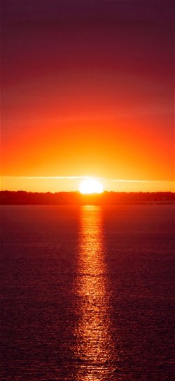 خلفية  غروب الشمس فوق مياه البحر الهادئة الرقيقة  للجوال