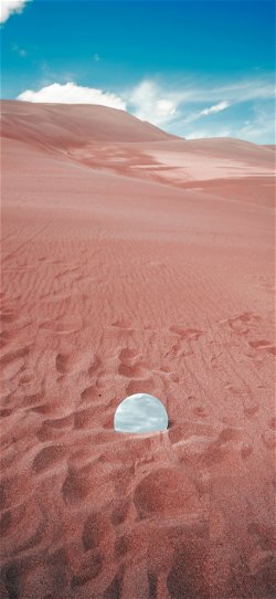 خلفية  مرآة دائرية مدفونة في رمال الصحراء الفسيحة  للجوال